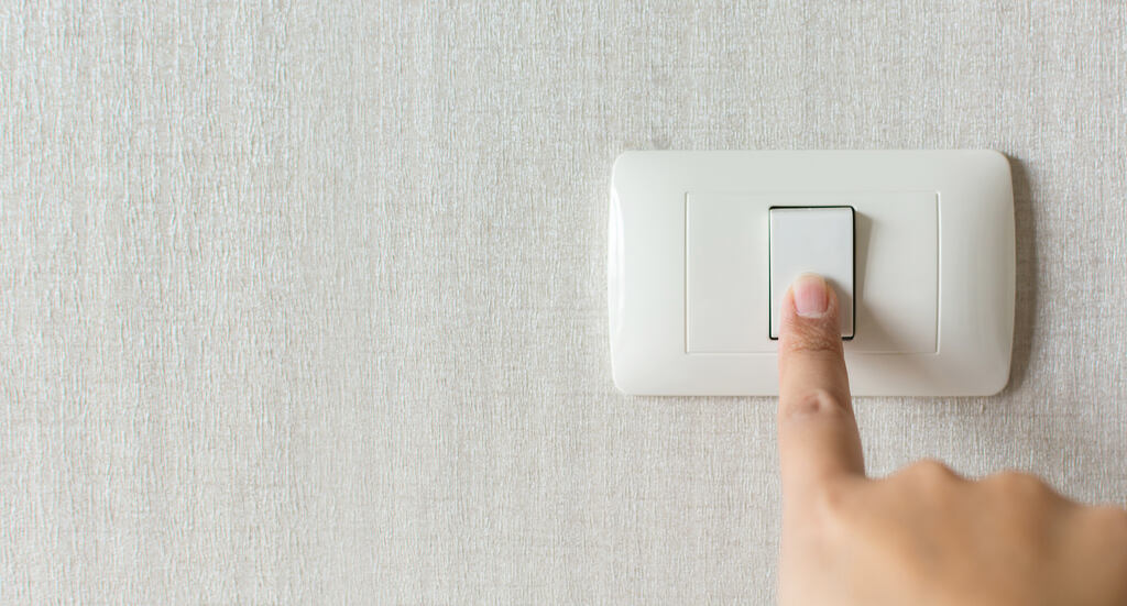 Pessoa desligando interruptor para reduzir o consumo de energia